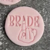 a pink circle with a hand engraved on itBride Middle Finger Fondant Stamp Cookie