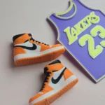 custom basketball jersey cake topper with name and number 23 and two orange high top sneaker cake toppers