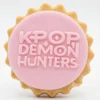 Round pink fondant cookie embossed with the text “KPOP DEMON HUNTERS” in chunky letters.