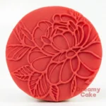 Red fondant cookie embossed all over with a detailed floral line-art pattern.