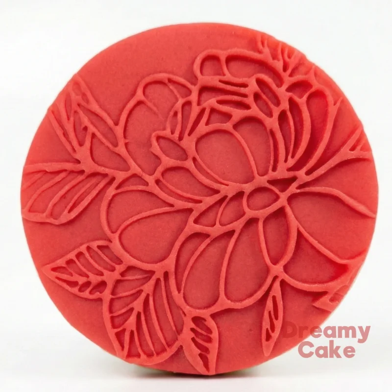 Red fondant cookie embossed all over with a detailed floral line-art pattern.